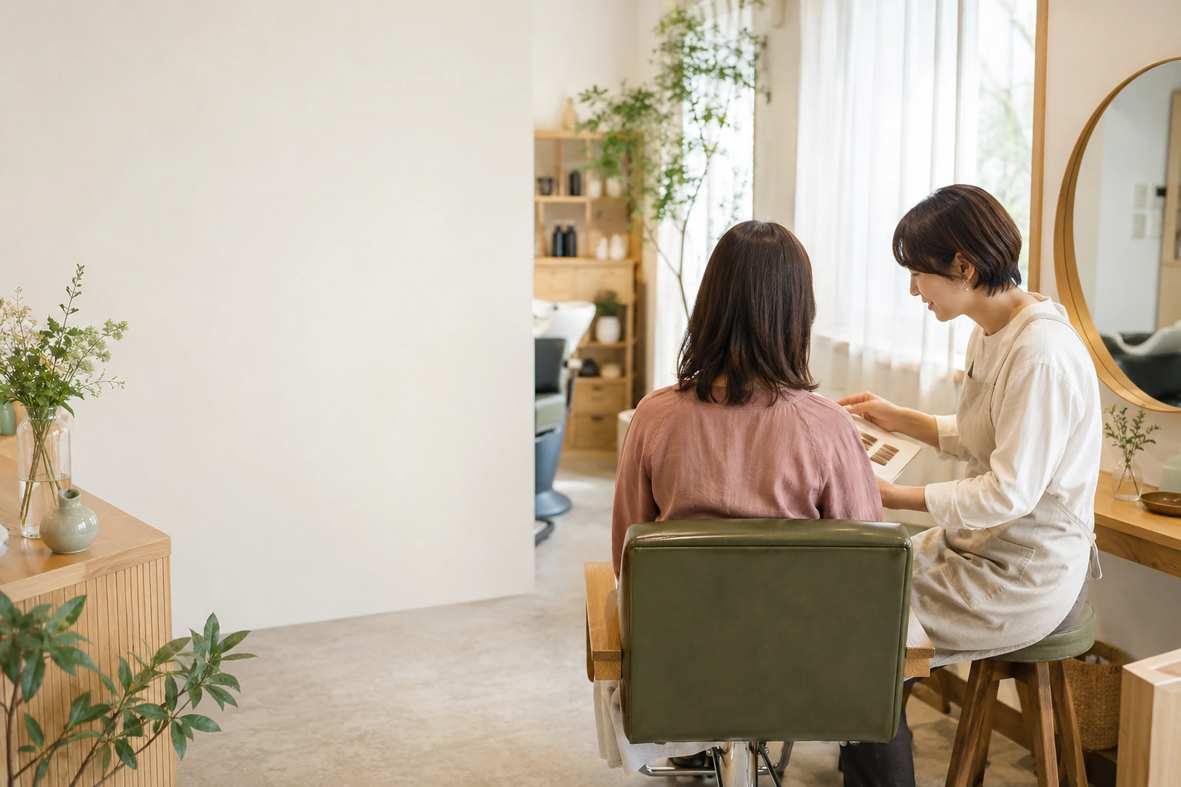 明るく落ち着いた美容室で美容師がお客様に髪型を提案するイメージ